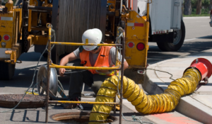 A worker looking into a manhole, which is a confined space