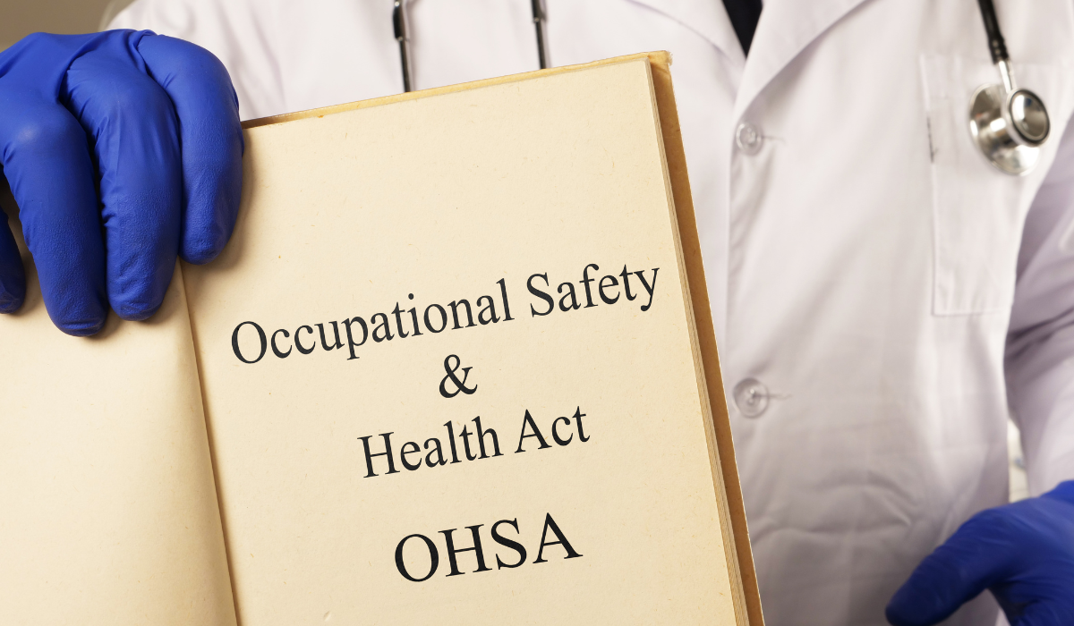 A person presumed to be a doctor holding a paper which reads "occupational safety & health act, OSHA"