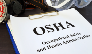 A clipboard holding a paper which reads "OSHA Occupational Safety and Health Act". Used for Injury and illness reports article Worksite Medical
