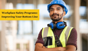 A worker wearing proper PPE with folded arms and smiling. There's a yellow text box with black text which reads, "Workplace Safety Programs: Improving Your Bottom Line"