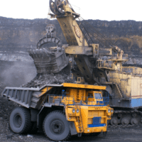 A mining operation at work. A large crane dumping dirt into a large dump truck. Working in mining operations requires MSHA silica physicals