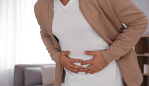 A person suffering from norovirus, clutching their abdomen in pain.